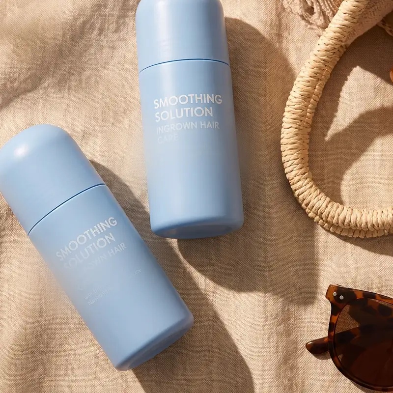 Two bottles on linen beside a woven bag and sunglasses